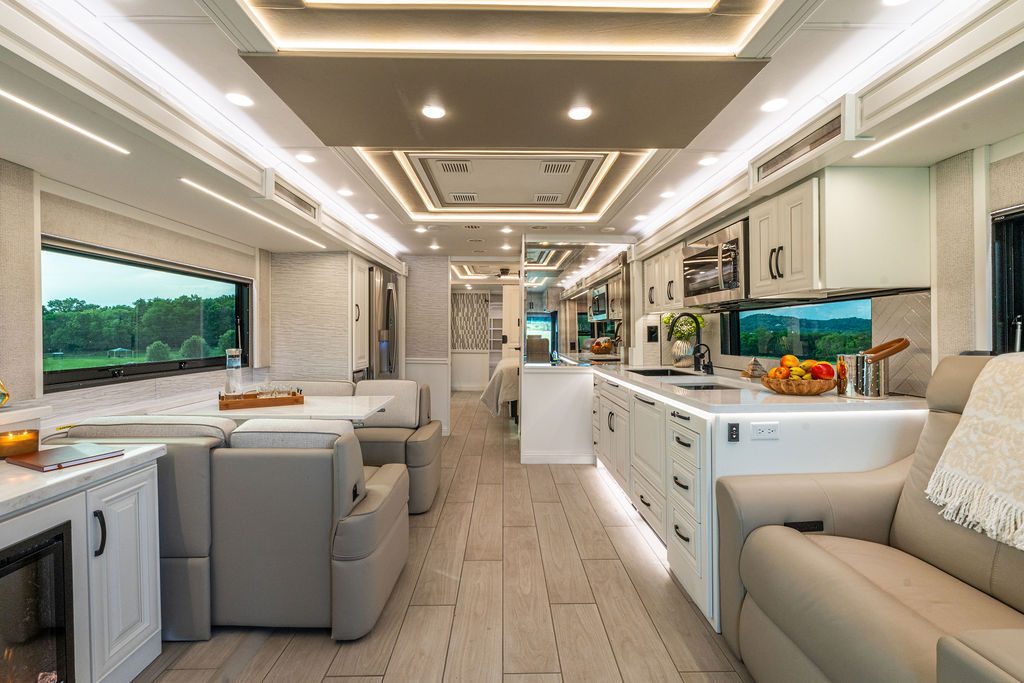 Main living area of the Cornerstone Series 6 with theater seating, galley kitchen, and cove lighting