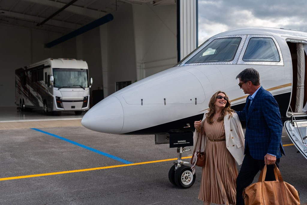 Couple stepping off a private jet with their luggage, the Cornerstone Series 6 waiting in the hangar behind