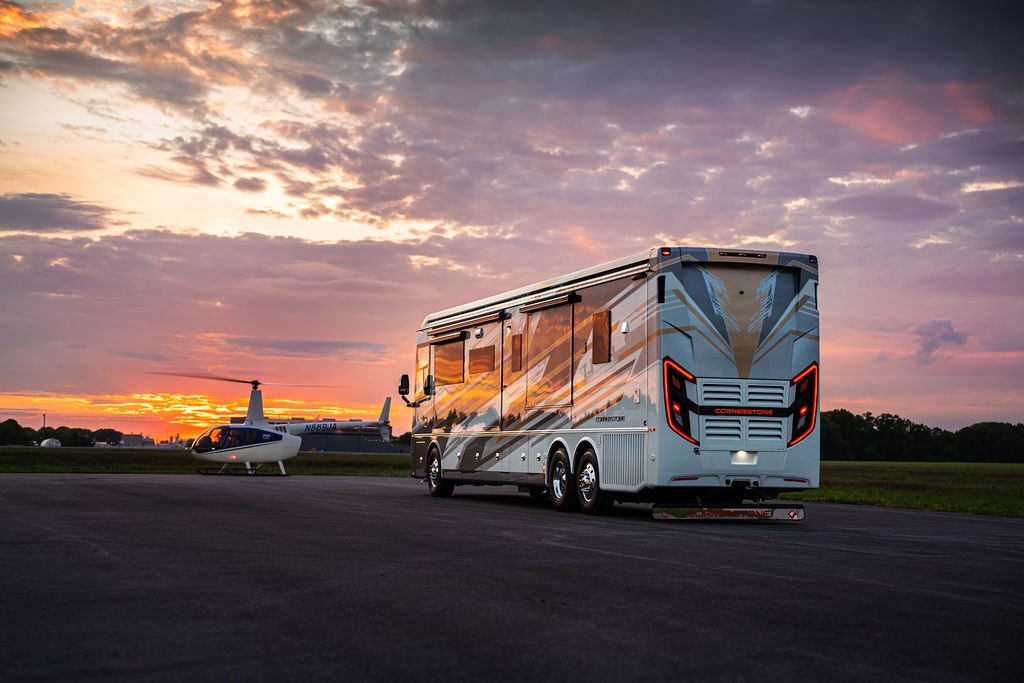 Cornerstone luxury coach and private jet under a sunset sky